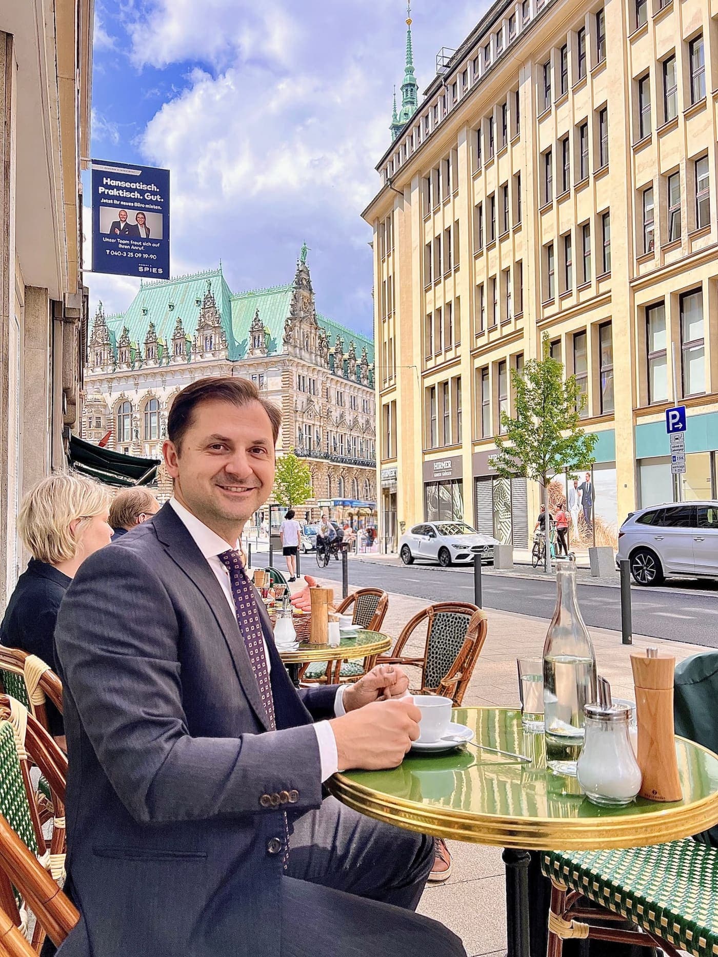 Ünal Eren — Hamburg'da bir kafede, arkaplanda Hamburg Belediye Sarayı